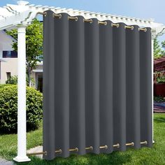 a large gray curtain hanging on the side of a house next to a white pergolan