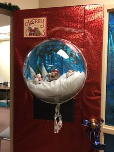 a snow globe is on display in an office cubicle, with santa's sleigh and other decorations