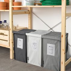 three storage bins sitting on top of a wooden shelf