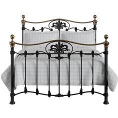 an iron bed frame with white sheets and fleur de lis