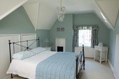 a bedroom with a bed, dresser and window in the middle of it is painted light blue