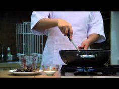 a man is cooking in a wok on top of the stove with a knife