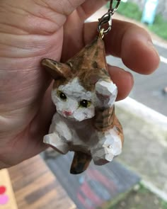 a person holding a small cat shaped keychain