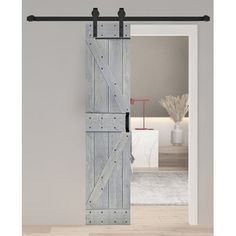 an open barn door with black hardware and wooden planks on the side, in front of a white wall