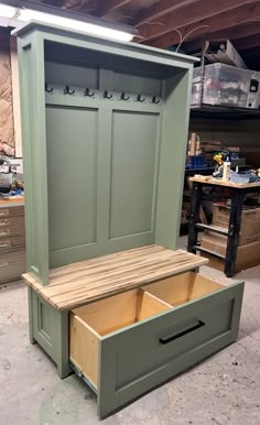 a wooden bench with two doors and drawers on the bottom, sitting in a garage