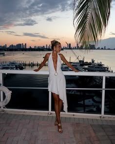 a woman is standing on a balcony overlooking the water and boats in the harbor at sunset