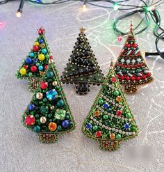 three christmas trees made out of bead and glass beads are sitting on a table