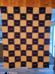 a cat sitting on the floor in front of a large quilt that has been made to look like squares