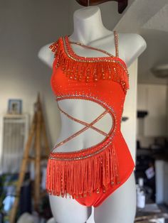 a female mannequin dressed in an orange belly dance costume with beads and fringes