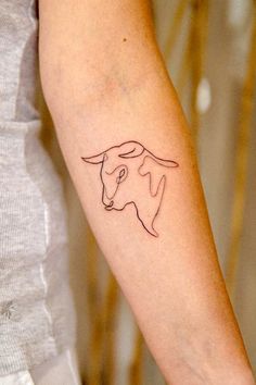 a woman's arm with a small tattoo of a bull on the left forearm