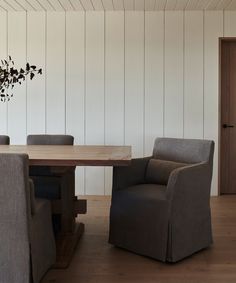 a dining room table with chairs around it and a vase on the wall next to it