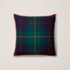 a green and red plaid pillow on a white wall