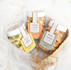 four jars filled with food sitting on top of a white cloth covered table next to each other