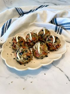 a white plate topped with meatballs covered in toppings on top of a marble counter