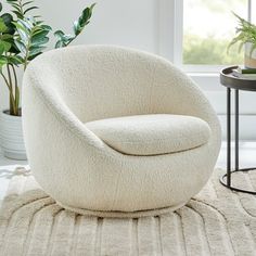 a white chair sitting on top of a rug next to a potted plant