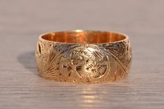 The Chartres: Antique Hand Engraved Band in Yellow Gold. Exuding timeless elegance, this antique yellow gold band boasts a generous width of 8.9mm, adorned with intricate hand-engraved scrolled and floral patterns. Crafted with meticulous attention to detail, the band showcases the artistry of its 14 karat yellow gold composition. Currently sized at 9.75, it can be delicately adjusted to achieve a perfect fit for an additional charge upon request. Love this piece, but don't have the money to spe Hand Engraved Wedding Band, Promise Rings Vintage, Antique Wedding Bands, Black Hills Gold Jewelry, Engraved Ring, Gold Sign, Black Hills Gold, Gold Engraving, Gold Velvet