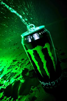 a can of monster energy drink is being splashed with water