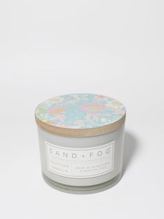 a candle that is sitting on top of a white surface with a flower print lid