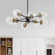 a modern chandelier hangs from the ceiling in a white room with built - in bookcases