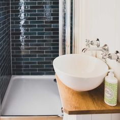 a white bowl sink sitting on top of a wooden counter next to a bath tub