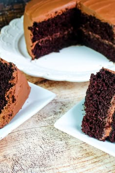 two slices of chocolate cake on plates with one slice missing from the cake and another half eaten