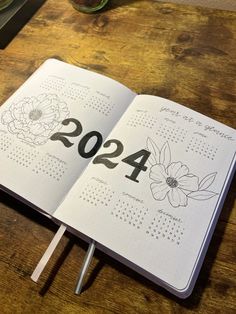 an open notebook with the numbers 4200 and flowers on it sitting on a wooden table