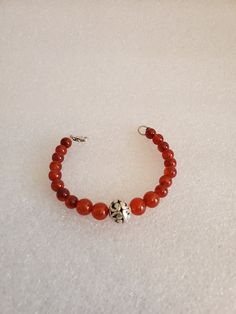 "This handmade Genuine Carnelian Beaded Bracelet was made on Silver Wire with round Genuine Carnelian Ball Beads. The bracelet is closed off using a 925-lobster clasp and jump ring. At the center is medium size Silver Ornate Metal Ball that is the focal point. This bracelet was handmade by Dulcinea for a small wrist and all items used are new. This bracelet would be a great gift and will arrive in a gift box with FREE SHIPPING. Measure: 6 5/8\" L Material: Genuine Carnelian in Round Shape, 925 L Amber Beaded Bracelets With Polished Beads As Gift, Hand-strung Silver Carnelian Jewelry, Silver Carnelian Jewelry Hand-strung, Silver Carnelian Hand-strung Jewelry, Amber Beaded Bracelets As Gift, Amber Beaded Bracelets For Gift, Healing Carnelian Beaded Bracelets, Red Carnelian Beaded Bracelets With Round Beads, Red Carnelian Beaded Bracelet With Round Beads