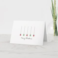 a white card with three christmas ornaments hanging from it