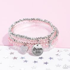 Reflective pink, defaced silver, reflective white, and smooth silver beads wrap around stretchy bands, and combine into a colorful stack along the wrist. The reflective, pink-beaded bracelet features a silver pendant with the phrase "dream BIG" stamped on it, while a defaced, silver-beaded bracelet features a silver star charm. Hanging from smooth, silver beads, a heart charm embossed with iridescent rhinestones adds a shimmery detail to the stack, resulting in a youthful, dreamy design. Due to Pink Charm Bracelet, Pink Beaded Bracelets, Pink Charm, Blue Beaded Bracelets, Snap Bracelets, Inspirational Bracelets, Wooden Bracelet, Beaded Wraps, Paparazzi Accessories