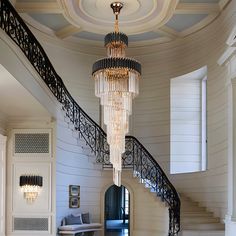 a chandelier hanging from the ceiling in a room with white walls and stairs