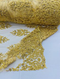 gold embroidered lace with sequins and beads on a white tableclothed surface