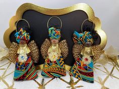 three african dolls sitting next to each other in front of a black background with gold trim