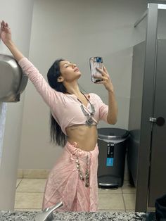 a woman is taking a selfie in the mirror with her cell phone while wearing a pink outfit