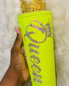 a hand holding up a yellow case with a crown on the top and diamond embellishments