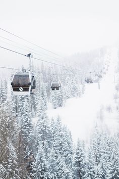 a ski lift with two people on it in the middle of a snow covered forest