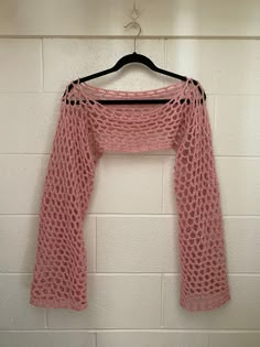 a pink sweater hanging on a white brick wall