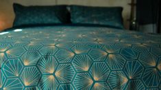 a bed with blue and gold bedspread, pillows and night lights on the headboard