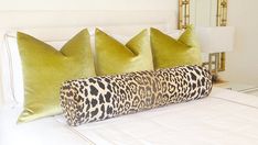 a bed with green pillows and leopard print pillow cases on top of it in a bedroom