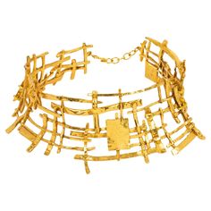 This spectacular around-the-neck necklace was designed in the 1990s by a French designer studio. The massive torque shape features a brutalist futuristic carved and see-thru design built with fine gilded metal. The piece is articulated in three curved elements and finished with a gilded metal chain and hook-closing clasp. The choker is signed on the underside with an oval logo that reads J Le. The designer has not been identified. Measurements: The necklace's inner circumference is 14.19 in (36 Brutalist Jewelry, Neck Necklace, Oval Logo, Metal Choker, Designer Studio, Metal Necklace, French Designer, La Face, Jewelry Lookbook