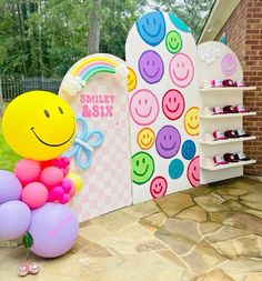 a smiley face balloon sitting on top of a bunch of balloons in front of a sign