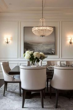 an elegant dining room with chandelier, chairs and flowers in vases on the table