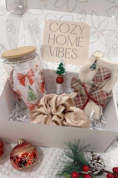 an open gift box with christmas decorations and gifts in it on a white tablecloth