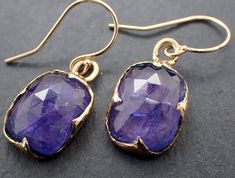 Introducing a beautiful and unique pair of Blue Tanzanite Dangle Earrings, handcrafted by the talented artisan Angeline using the traditional lost wax process. These stunning earrings are the perfect way to add a touch of elegance and sophistication to any outfit. Each earring features a breathtaking 12.5mm x 9.5mm blue Tanzanite gemstone, selected for its stunning color and quality. The Tanzanite is suspended from a delicate 14K gold wire, creating a graceful dangle style that will add a touch Elegant Tanzanite Dangle Earrings, Fine Jewelry Tanzanite Drop Earrings, Elegant Gold Tanzanite Earrings, Wedding Tanzanite Gemstone Earrings, Elegant Hand Forged Blue Earrings, Tanzanite Gemstone Earrings For Wedding, Luxury Tanzanite Drop Earrings, Elegant Handmade Sapphire Jewelry, Elegant Hand Forged Dangle Jewelry