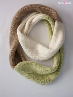 two scarves are sitting on a white surface, one is green and the other is beige