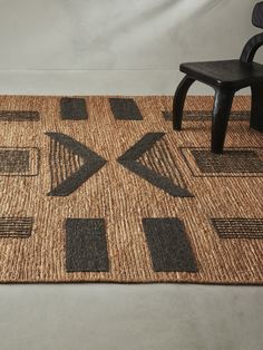 a chair sitting on top of a rug next to a wooden table with a black chair