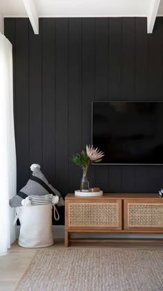 a living room with black walls and wicker baskets on the coffee table next to it