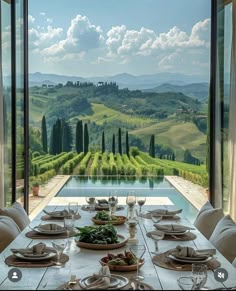 a dining table with plates and place settings in front of an outdoor pool overlooking the countryside