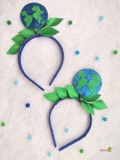 two headbands made out of paper with green leaves and the earth on them