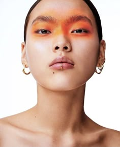 a woman with orange makeup and piercings on her face