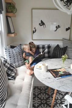 two children are sitting on a couch reading a book in the living room with black and white decor